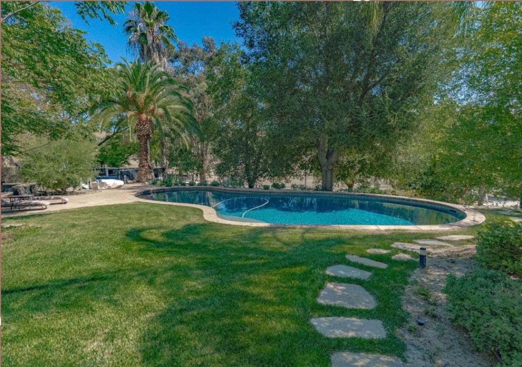 Resort-style swimming pool surrounded by lawn and trees